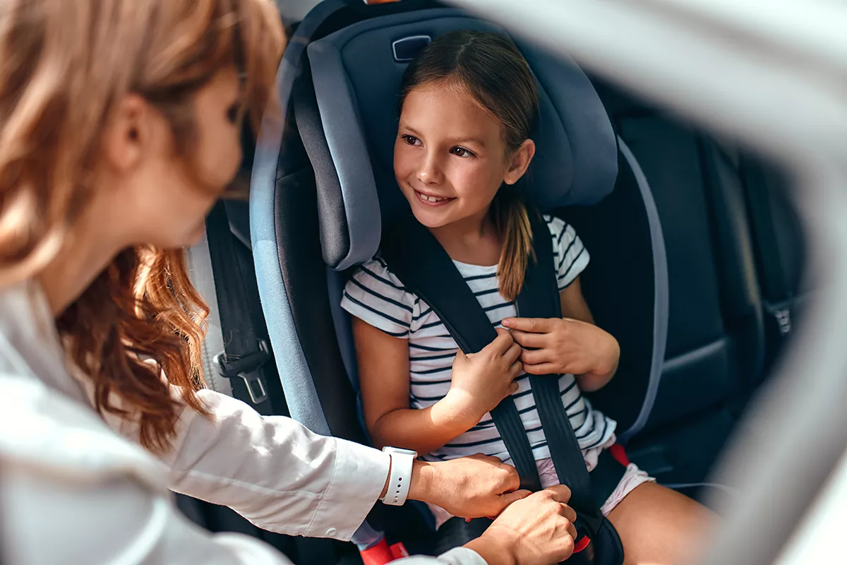 Woman securing child in car seat