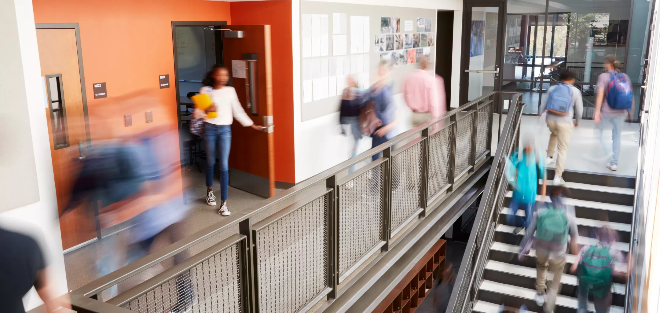 Busy high school corridor with blurred students and staff. 